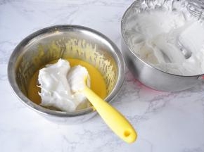 取三分之一蛋白霜加入蛋黄糊，用翻拌加切拌的手法拌匀。