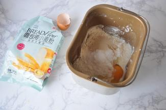 先将除黄油外的所有材料放在面包机桶中。放时注意顺序，先放液体类，然后再放面粉，最后盐和糖放对角，酵母放在中间。我用的是一个鸡蛋大约去壳50克，然后再加入牛奶，蛋和牛奶的总重量为180克。