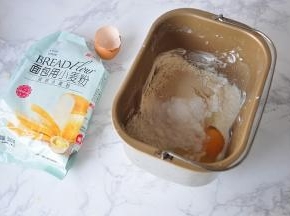 先将除黄油外的所有材料放在面包机桶中。放时注意顺序，先放液体类，然后再放面粉，最后盐和糖放对角，酵母放在中间。我用的是一个鸡蛋大约去壳50克，然后再加入牛奶，蛋和牛奶的总重量为180克。