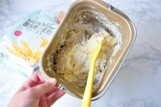 先将面包机桶中的食材搅拌几下，这样面包机在揉制时不易溅粉，混合更充分。如果用厨师机更省事，如果用手揉也可以。