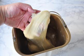 一直将它揉成光滑的面团，然后加入切成小块的黄油揉成扩展阶段。面包机我一般会选择和面程序15分钟后放