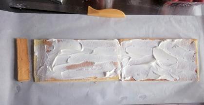 把两块蛋糕拼接在一起，底部铺油纸，涂上一层淡奶油，如图