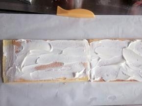 把两块蛋糕拼接在一起，底部铺油纸，涂上一层淡奶油，如图