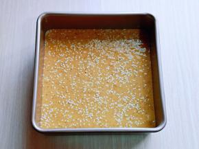 拌好的红枣枣泥糊倒入模具中，用刮刀刮平整，轻轻震几下，将气泡震出，再撒上白芝麻。