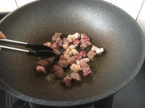 将牛肉粒一面煎至变色，用夹子将牛肉粒反过来，煎另外一面，同样煎至变色。