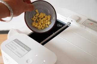 预热结束后根据提示从投料口放入10g植物油和生姜粒，投料完毕后点击开始键进行翻炒；