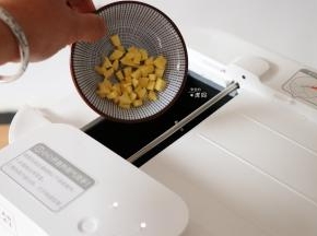 预热结束后根据提示从投料口放入10g植物油和生姜粒，投料完毕后点击开始键进行翻炒；