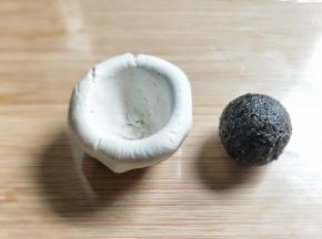 将面团窝出圆窝状，放入黑芝麻球。
