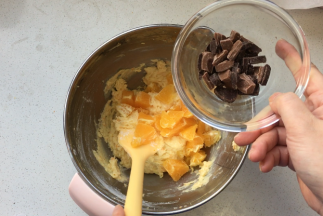 巧克力切成小块，橙子肉分成两部分，一部分切成小块，用于蛋糕主体部分，另一部分掰成橙子瓣，用于蛋糕表面装饰用。巧克力预留15克作为表面装饰，将小块的橙子块与巧克力放入到面糊中。简单搅拌