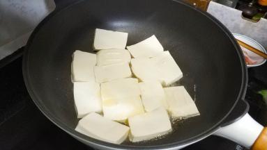锅里热油放入沥干水分的豆腐片