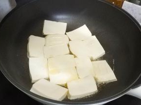 锅里热油放入沥干水分的豆腐片