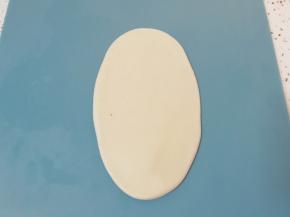 包好的油酥皮收口向上压扁，擀成椭圆形卷起。