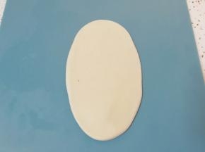 包好的油酥皮收口向上压扁，擀成椭圆形卷起。