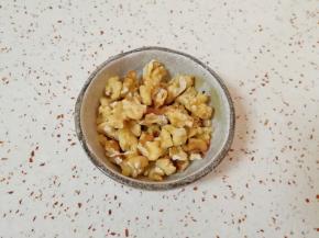 核桃仁烤熟以后趁热揉搓一下去皮(不用完全去掉)，用刀切碎。