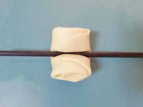 用筷子将松弛好的卷卷从中间压一下。