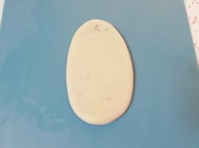 将包好馅的枣泥核桃卷收口向下轻轻压扁，擀成椭圆形。