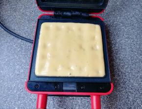 预热好的华夫饼早餐机烤盘里倒入准备好的华夫饼面糊，盖上盖子加热4-5分钟。