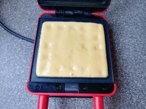 预热好的华夫饼早餐机烤盘里倒入准备好的华夫饼面糊，盖上盖子加热4-5分钟。