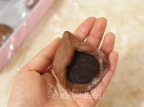 松弛好的面团压扁，包入2个巧克力币，捏紧收口，最后将面团团圆。