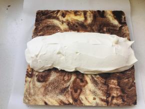 12、将打发的奶油堆放与蛋糕片中间位置，掀起蛋糕两头将奶油包裹在中间