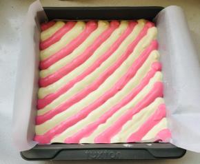 烤盘中放入油纸，以对角斜线的方法，将两个颜色的蛋糊交替挤于烤盘内