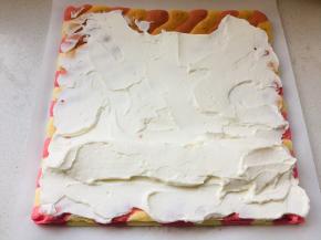 出炉后置于晾网上，取另一张油纸置于蛋糕上，翻面撕掉油纸，将打发的淡奶油涂抹在蛋糕一面上