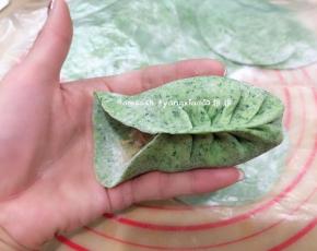 取一张包子皮码上适量的馅料，用拇指和食指捏一个褶儿，然后顺着食指方向捏褶，捏完稍整形整成弯弯的柳叶形状