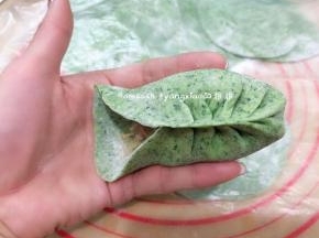 取一张包子皮码上适量的馅料，用拇指和食指捏一个褶儿，然后顺着食指方向捏褶，捏完稍整形整成弯弯的柳叶形状