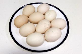 鸡蛋煮完放凉或放入冷水中浸泡会，用勺子把鸡蛋壳敲裂。