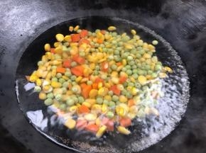 浸泡糯米的过程，把红萝卜、豌豆一次、玉米粒依次放入锅中煮沸