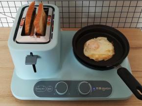 鸡蛋煎到表面凝固，翻面继续煎熟，吐司烤热后会自动弹出，取出来放一边