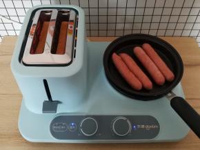 把香肠放入煎锅里，左边多士炉继续烤吐司片