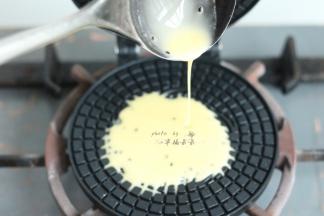 用勺子舀一勺面糊倒入蛋卷模具中间位置，面糊会自动朝旁边溢开，溢开至模具3/4圆周满时，立即合上蛋卷模，放在燃气灶上小火加热1分钟，然后翻过来模具反面加热40秒左右，直至蛋卷呈微黄色