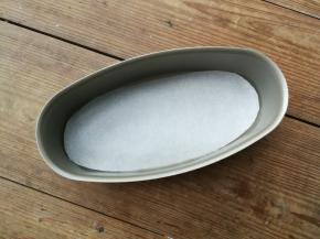 椭圆形奶酪蛋糕模具底部事先垫一张油纸，侧边涂抹一层薄薄的黄油防粘