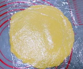 将冷藏后的面团隔着保鲜膜，用擀面杖擀薄