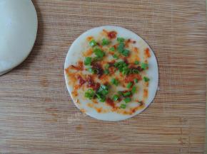 然后将切好的葱花均匀的撒在饺子皮上面，多少随意。