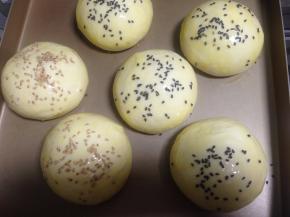 先在汉堡胚表面刷蛋液，然后撒上适量熟芝麻，同时烤箱180度预热