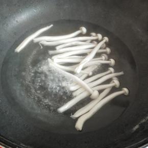 再把锅里做水烧开，下白玉菇焯水两分钟左右，捞出来过一遍凉开水