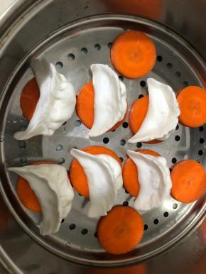 像包饺子那样包好，摆在胡萝卜段上。(摆胡萝卜上可以防止粘粘。)