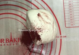 将揉好的面团平均分割成两份，其中一份加入红曲粉继续揉，揉到红曲粉和面团完全混合均匀。剩下的一半放回面包机桶内，防止面团表面变干