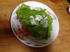 
面包胚底部放入一片生菜，以个人口味挤上少许沙拉酱