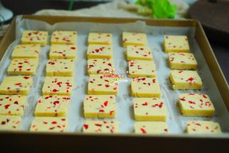 时间到后，取出来，用一把锋利的刀切成片，有间隔地摆放在铺了油纸的烤盘上。烤箱提前预热，上下火185度烘烤15分钟就好了。冷冻曲奇的时间不要过长，否则切片的时候会碎。