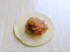 取一张饺子皮，放入馅料，将饺子皮对折。