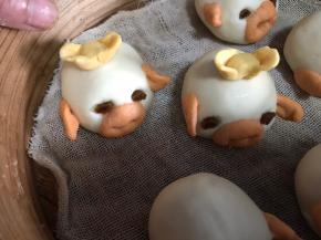 再把南瓜面团做成金元宝，放在猪背上，放入铺好纱布的蒸屉里，醒发10分钟后放入开水锅中蒸10分钟即可