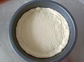 将面团擀成和披萨盘一般大小的圆，放入披萨盘，压出边边来，用叉子在饼底戳一些孔洞