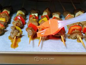 15分钟后取出烤盘，将肉串两面刷上食用油。