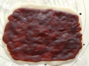 用擀面杖擀成长方形，然后撕开保鲜袋，在糯米片上铺上一层豆沙馅。