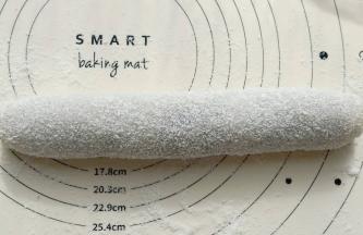 铺好豆沙借助下面的保鲜袋卷起来，然后在硅胶垫上撒一层椰蓉。把糯米卷放在椰蓉上滚一下。