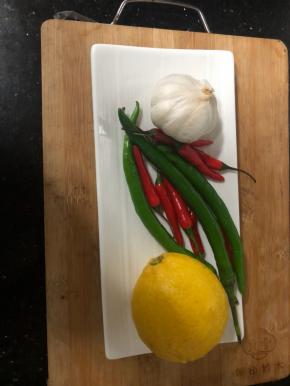 准备泡鸡爪的材料，辣椒切小段，柠檬用盐清洗外表以后切薄片，大蒜去皮切小粒。