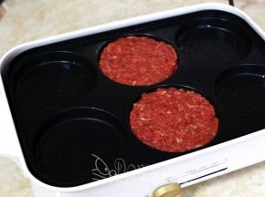 OSTINI多功能料理锅的六圆盘薄薄刷一层油，把牛肉团分成2等份，在六圆盘中团圆压扁。